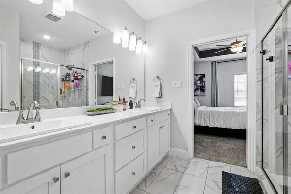 a spacious en suite bathroom with double sink and mirror
