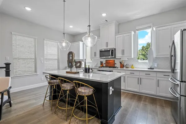 a kitchen with stainless steel appliances granite countertop a table chairs stove a sink dishwasher a refrigerator and microwave with wooden floor