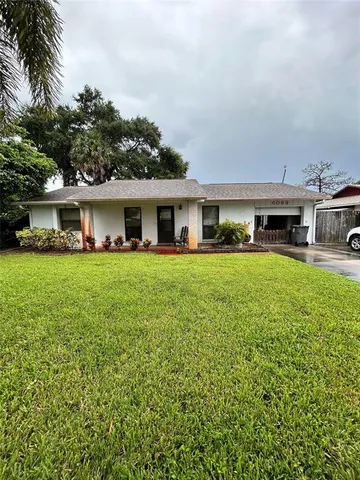 a view of house with a big yard and potted plants