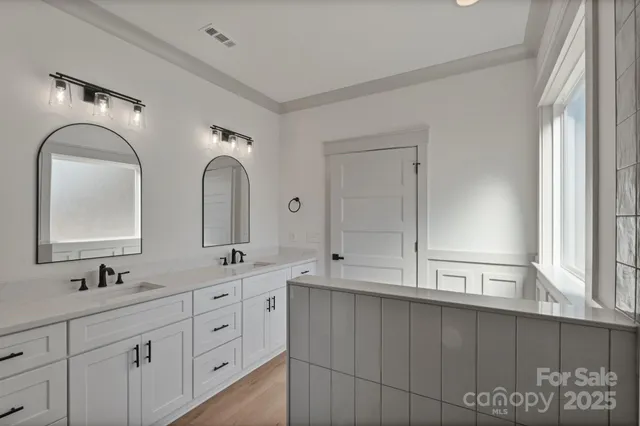 a bathroom with double vanity sink two mirror and window