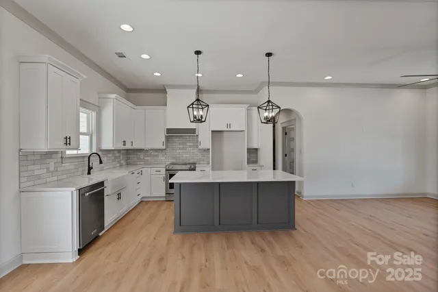 a large kitchen with granite countertop a sink a counter space appliances and cabinets