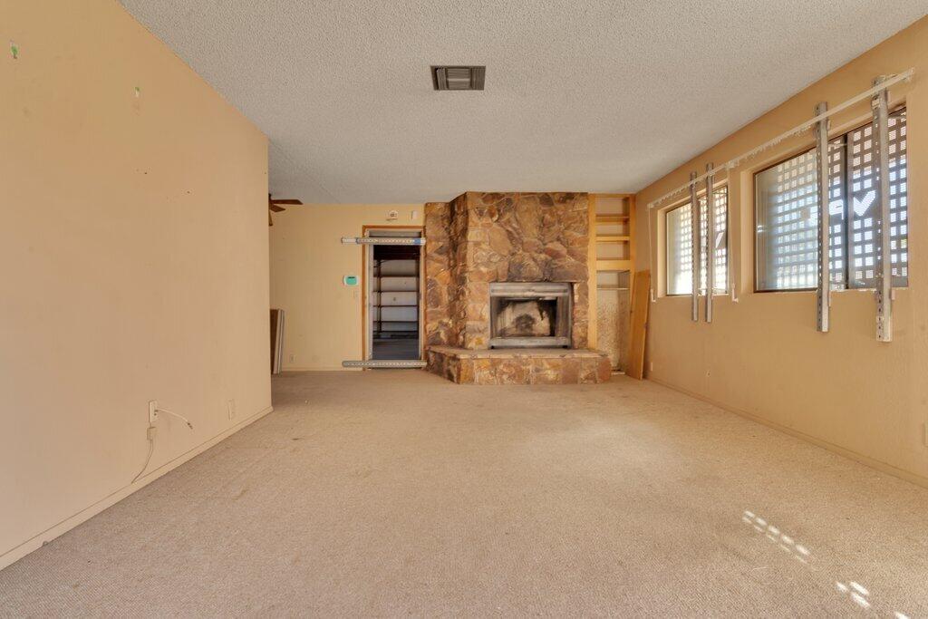 925 Inca Trail Yucca Valley, CA 92284 - Photo 9 of 31 an empty room with a fireplace and windows