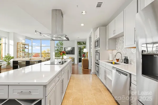 a large open kitchen with stainless steel appliances granite countertop a lot of counter space and wooden floors