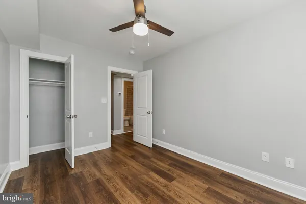 an empty room with wooden floor closet and ceiling fan