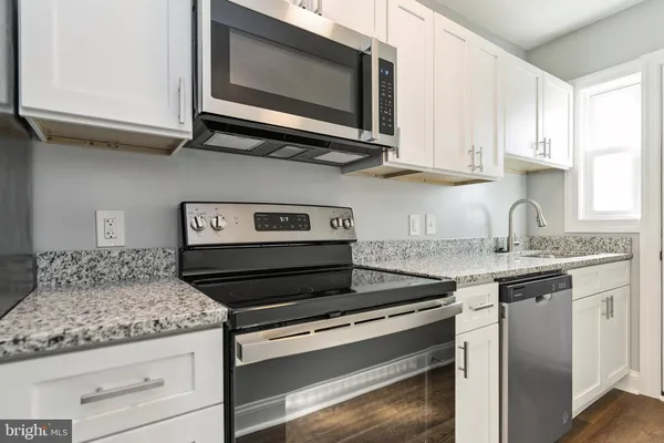 a kitchen with stainless steel appliances granite countertop white cabinets and a stove top oven