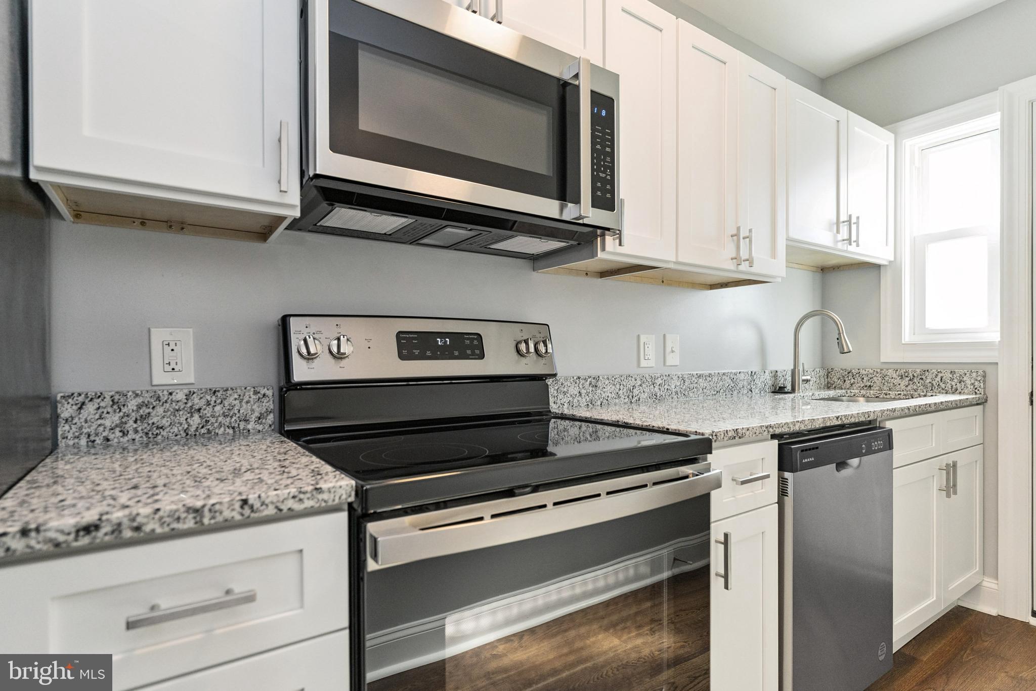 2021 E Street Northeast, Unit 2 Washington, DC 20002 - Photo 9 of 14 a kitchen with stainless steel appliances granite countertop white cabinets and a stove top oven