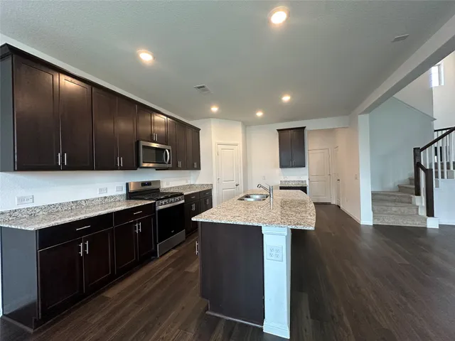 a large kitchen with stainless steel appliances wooden cabinets and wooden floor