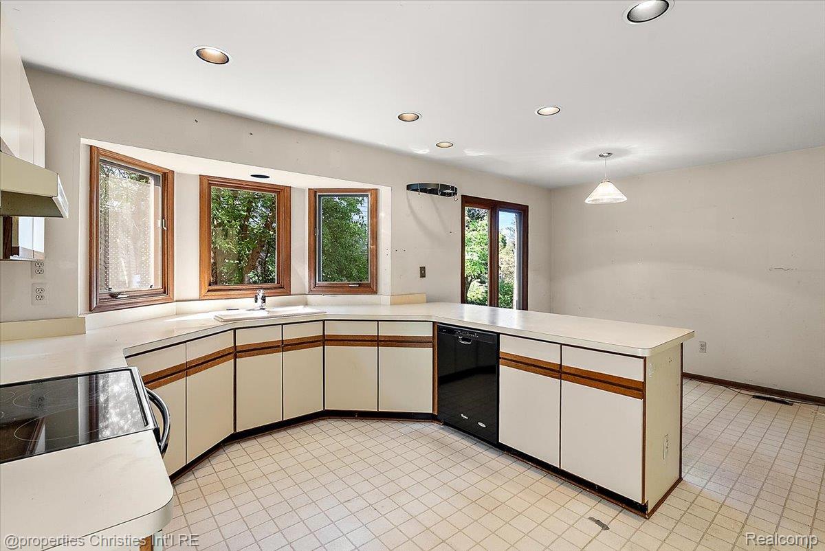 37224 Chesapeake Road Farmington, MI 48335 - Photo 26 of 50 Kitchen featuring a curved peninsula with built-in dishwasher, white cabinetry with wood-finish accents, and a bay window overlooking exterior greenery