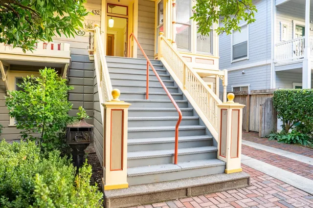 a view of a house with entrance stairs and a large tree