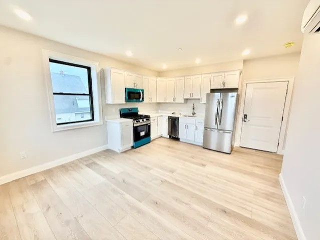 a view of kitchen with stainless steel appliances refrigerator stove microwave and cabinets