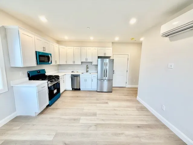 a large kitchen with stainless steel appliances granite countertop a stove a sink and a refrigerator