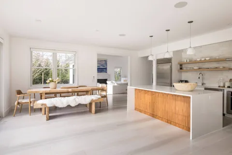 a large white kitchen with a large window and stainless steel appliances