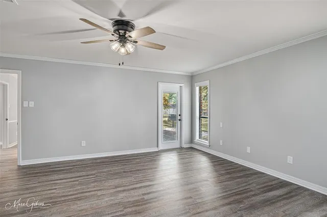 a view of an empty room with window and wooden floor