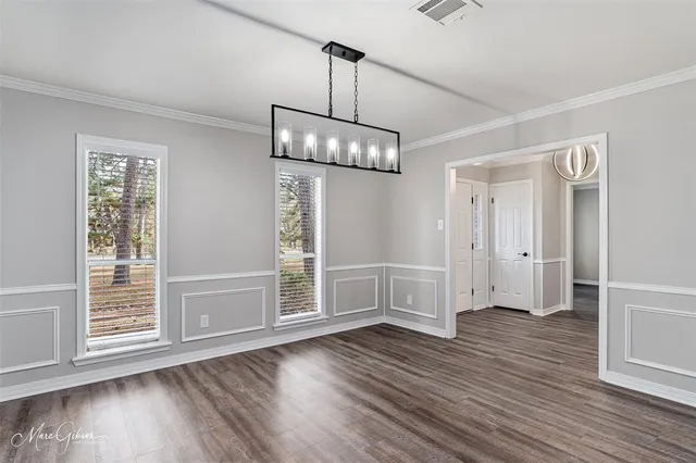 an empty room with wooden floor mirror and windows
