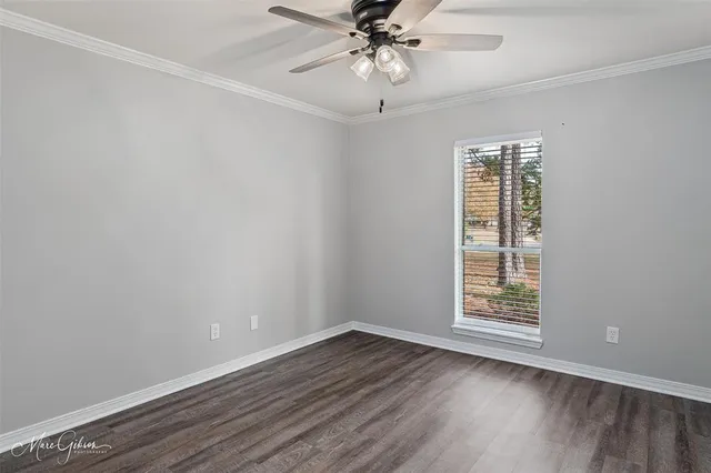 an empty room with wooden floor chandelier fan and windows