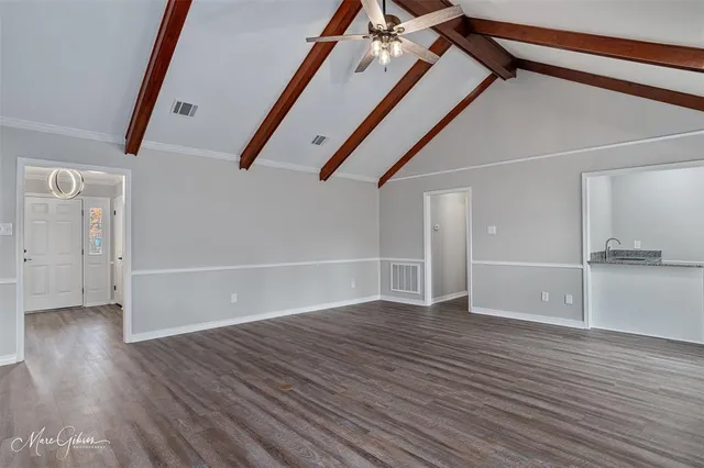 a view of an empty room with wooden floor and stairs