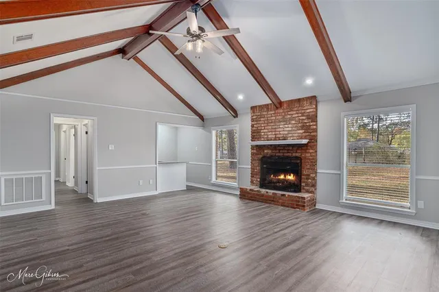 a view of a livingroom with wooden floor a fireplace and window