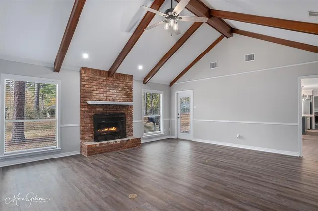 a view of an empty room with wooden floor fireplace and a window