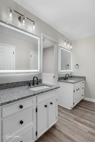 a bathroom with a granite countertop double vanity sink and mirror