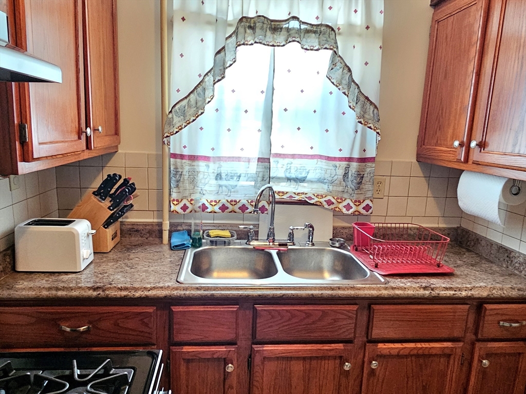 460 William Street Fall River, MA 02721 - Photo 3 of 23 a kitchen with a sink a stove and a wooden floor