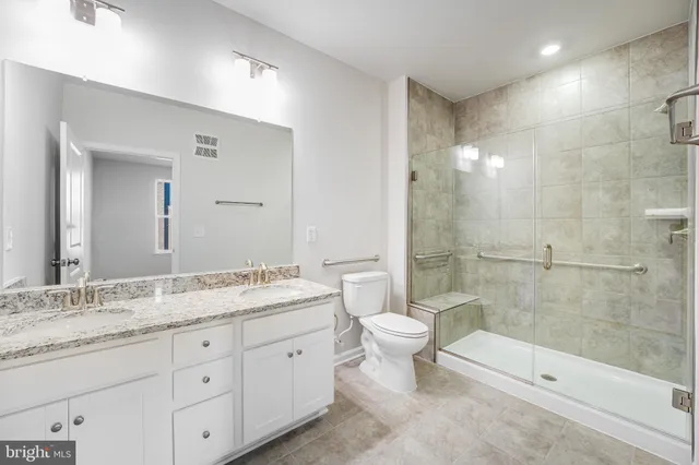 a bathroom with a granite countertop sink a toilet and a mirror