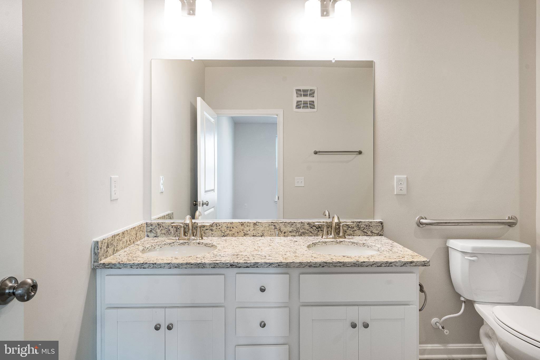 4003 Seaside Alder Road, Unit 203 Bowie, MD 20720 - Photo 20 of 22 a bathroom with a granite countertop sink a toilet and a mirror