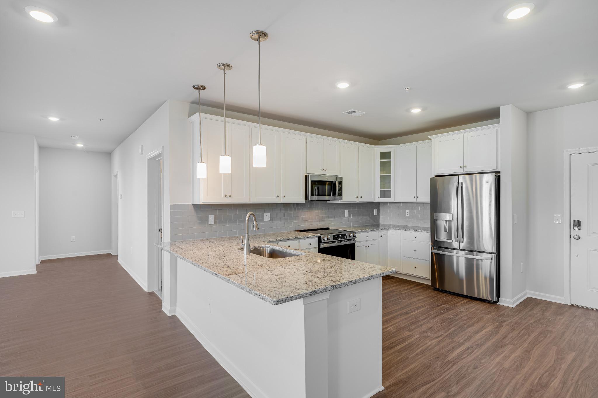 4003 Seaside Alder Road, Unit 203 Bowie, MD 20720 - Photo 5 of 22 a kitchen with stainless steel appliances granite countertop a refrigerator a sink dishwasher a stove and a refrigerator with wooden floor