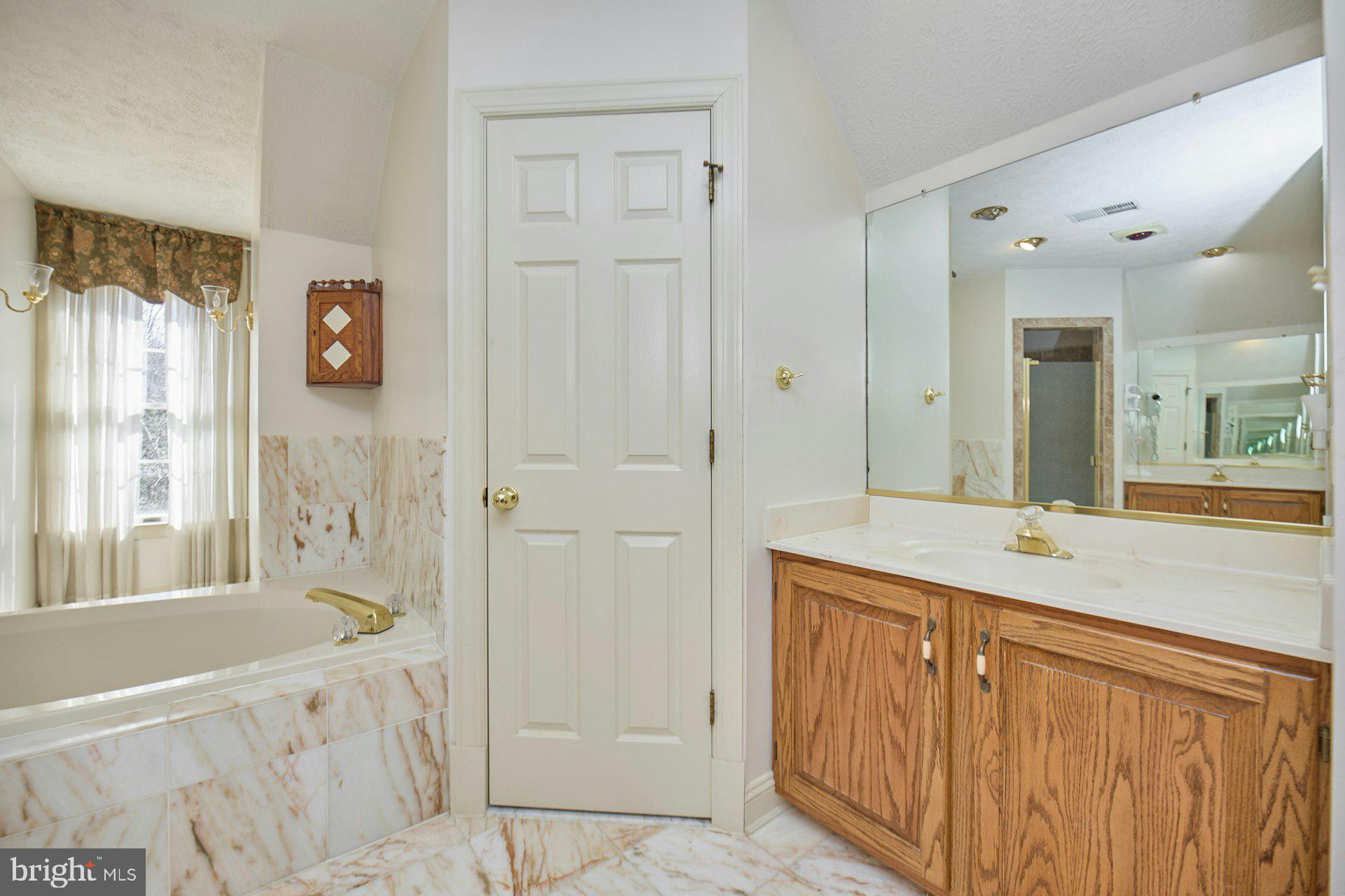 6051 Adams Drive La Plata, MD 20646 - Photo 39 of 72 a bathroom with a granite countertop sink a mirror a bathtub and next to a window
