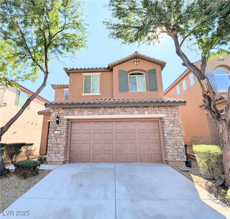 7011 Amapa Road Las Vegas, NV 89178 - Photo 1 of 32 Mediterranean / spanish house featuring stone siding, stucco siding, concrete driveway, and an attached garage
