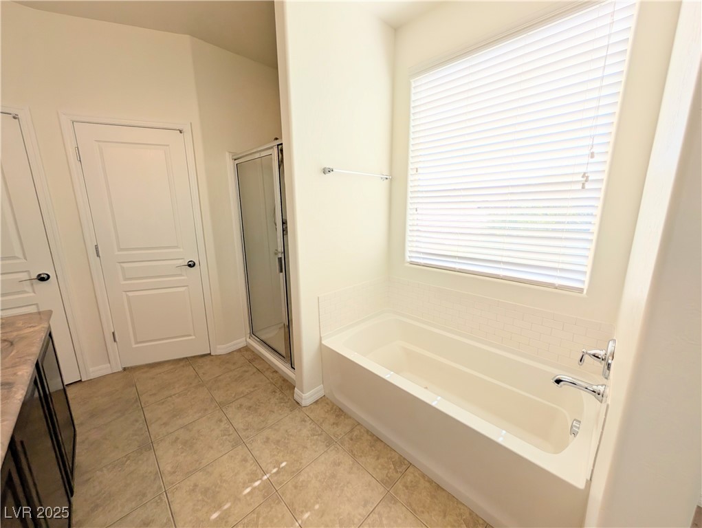 7011 Amapa Road Las Vegas, NV 89178 - Photo 17 of 32 Full bath featuring vanity, a shower stall, light tile patterned flooring, and a bath