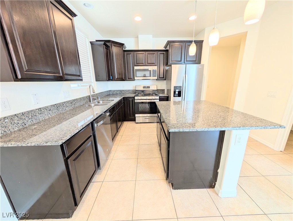 7011 Amapa Road Las Vegas, NV 89178 - Photo 5 of 32 Kitchen featuring appliances with stainless steel finishes, dark brown cabinetry, light stone countertops, light tile patterned floors, and recessed lighting