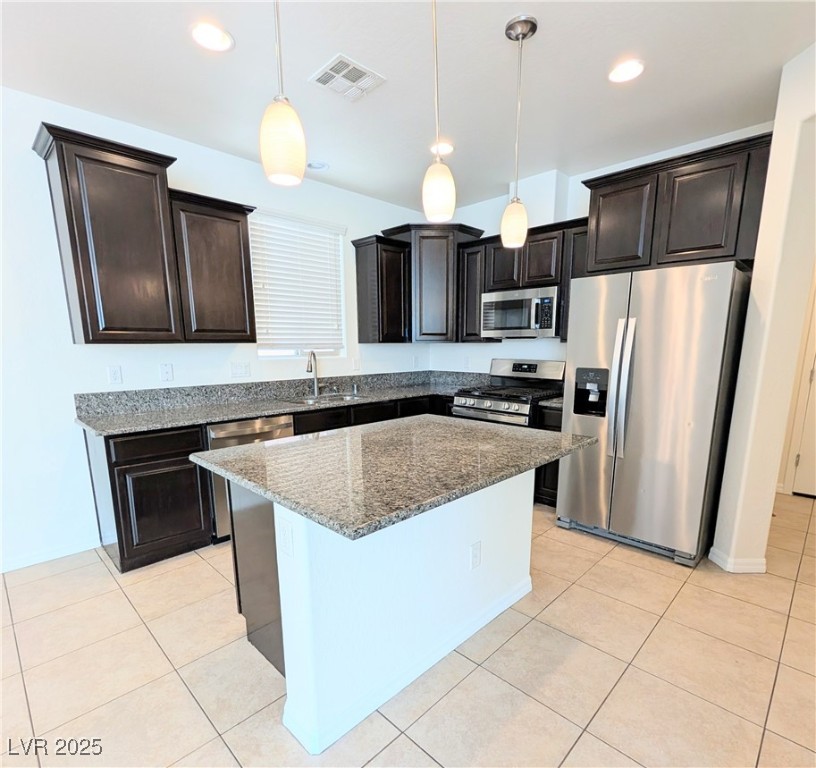 7011 Amapa Road Las Vegas, NV 89178 - Photo 6 of 32 Kitchen featuring stainless steel appliances, dark brown cabinetry, hanging light fixtures, light stone counters, and recessed lighting
