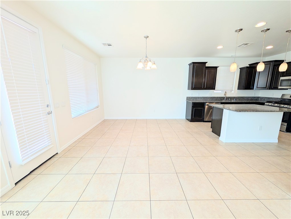 7011 Amapa Road Las Vegas, NV 89178 - Photo 8 of 32 Kitchen with decorative light fixtures, light tile patterned flooring, stainless steel appliances, a chandelier, and dark stone counters