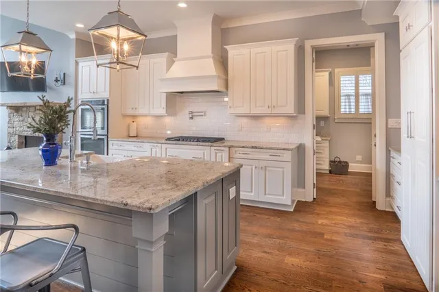 a kitchen with stainless steel appliances granite countertop a sink a stove and a wooden floors