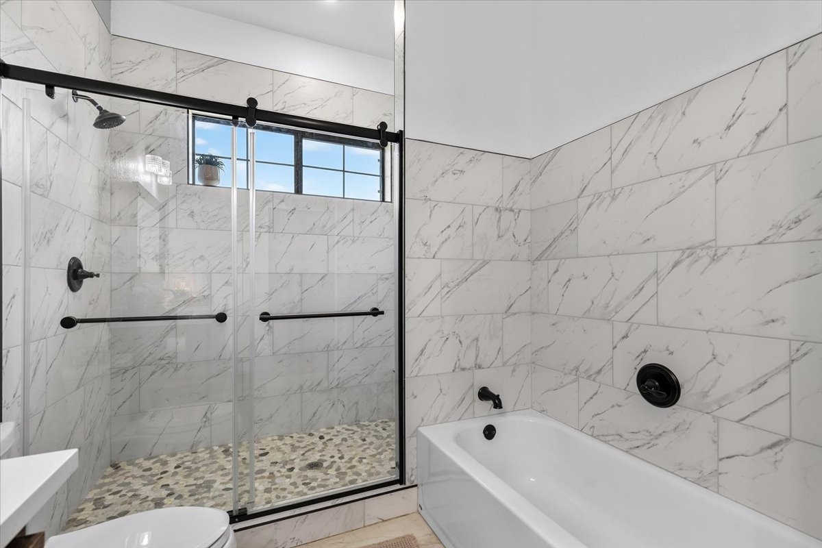 175 Wilson Road Elgin, TX 78621 - Photo 25 of 40 A closer look at this guest bath shows off the great layout—you get the best of both worlds with a separate deep soaking tub and a walk-in shower with pebble tile floors.