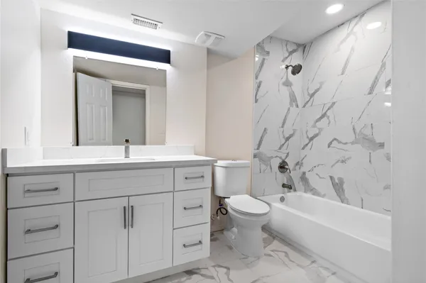 a bathroom with a double vanity sink toilet mirror and bathtub