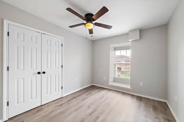 an empty room with wooden floor and ceiling fan