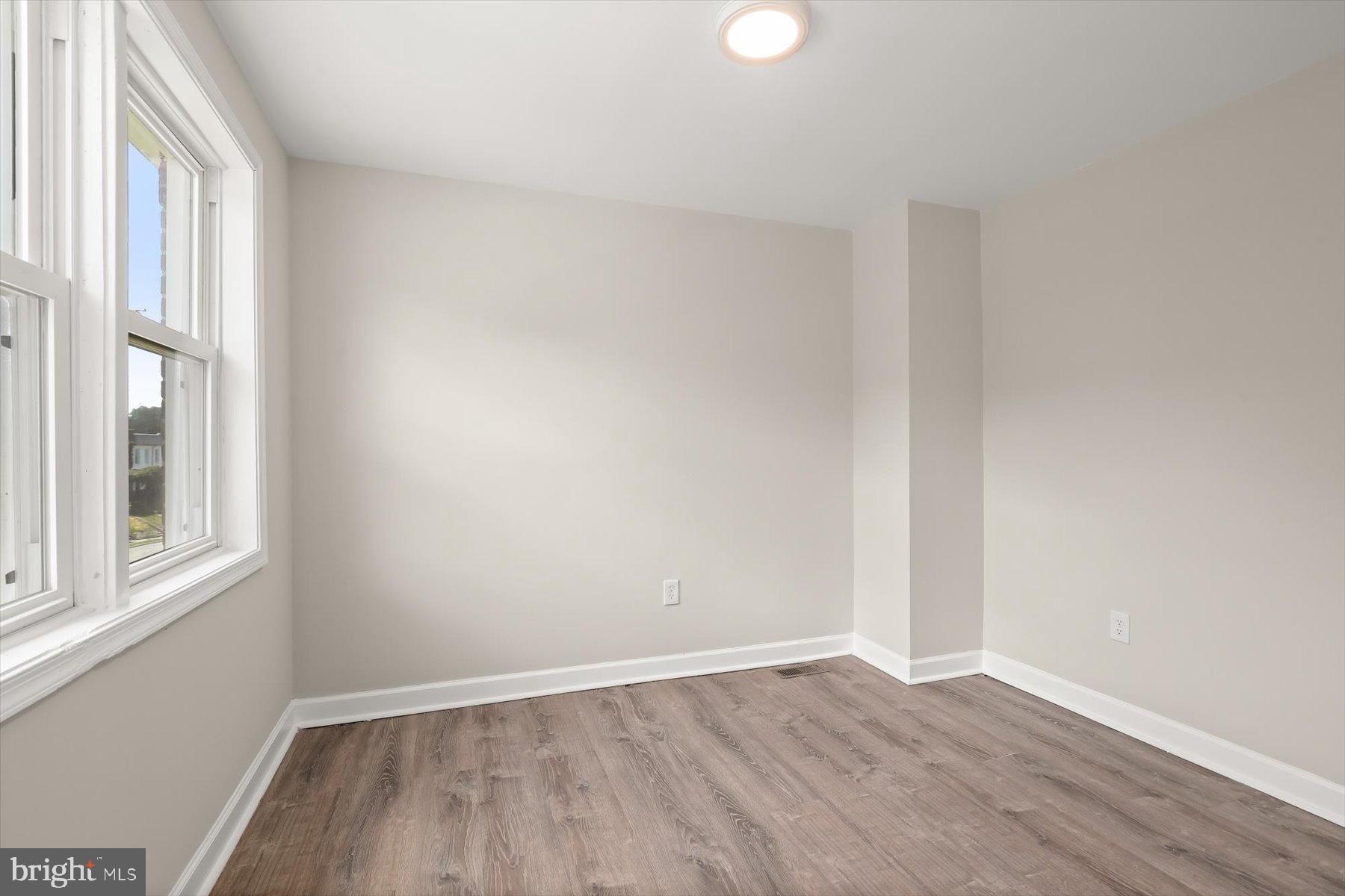 1044 Ellicott Driveway Baltimore, MD 21216 - Photo 15 of 26 a view of an empty room with wooden floor and a window