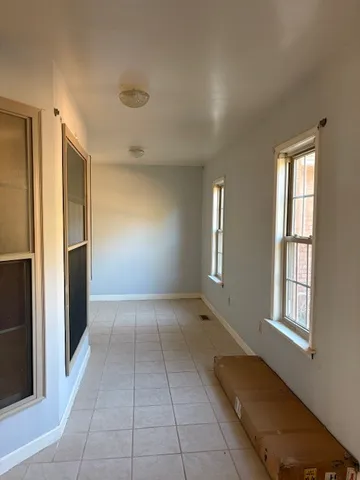 an empty room with wooden floor chandelier fan and windows