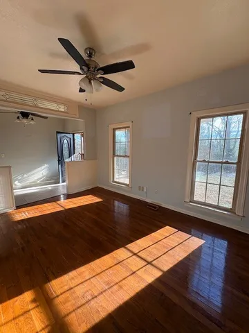 a view of empty room with wooden floor and fan