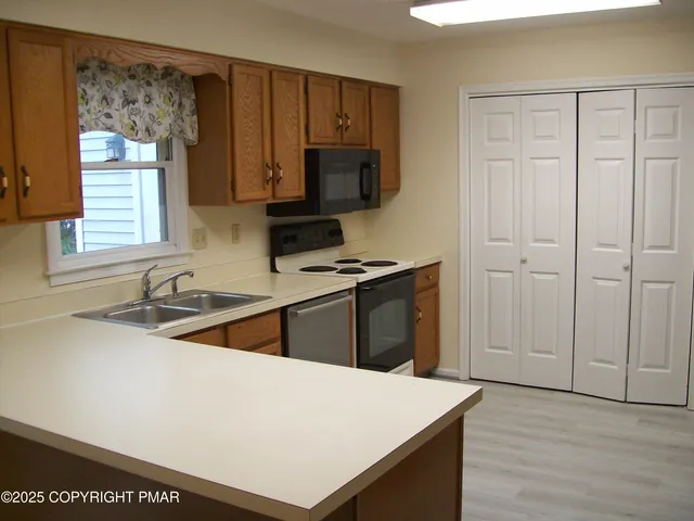 a kitchen with stainless steel appliances granite countertop a sink dishwasher a stove and a refrigerator with wooden floor