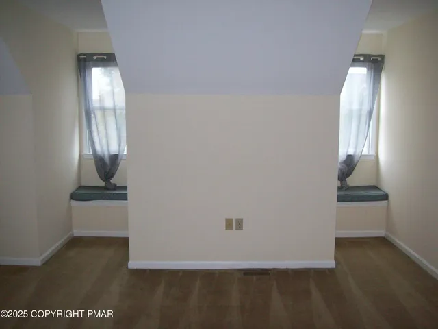 an empty room with wooden floor mirror and windows