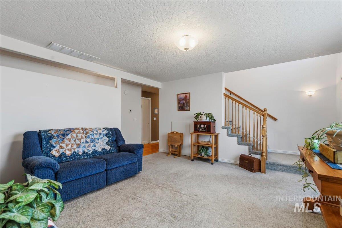2331 Gulley Road Homedale, ID 83628 - Photo 16 of 46 Carpeted living area featuring a wood staircase with a carpeted runner, and an overhead flush-mount light fixture