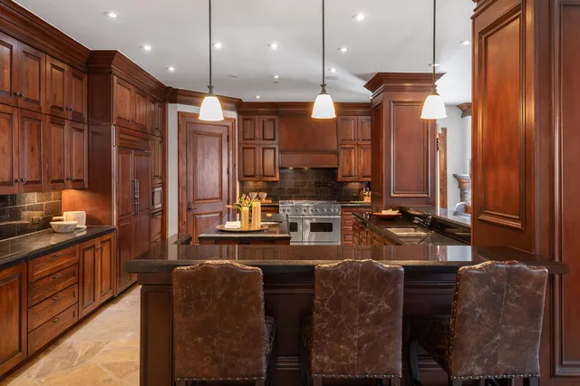 a kitchen with stainless steel appliances kitchen island granite countertop a stove a sink and a refrigerator