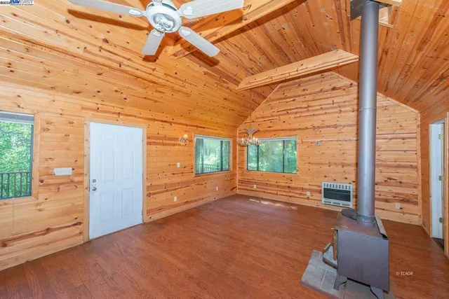 a view of an empty room with wooden floor and fence