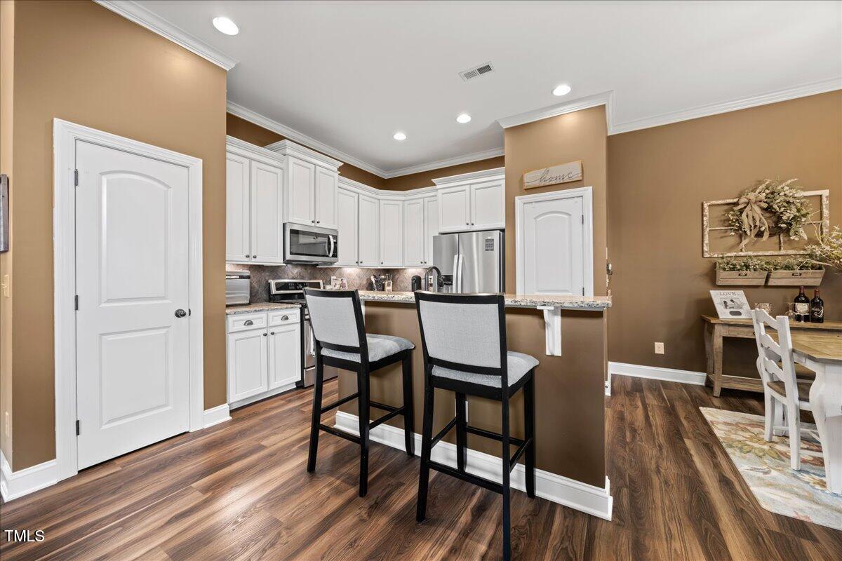 1300 Formal Garden Way Raleigh, NC 27603 - Photo 11 of 45 a kitchen with stainless steel appliances a dining table chairs stove and cabinets