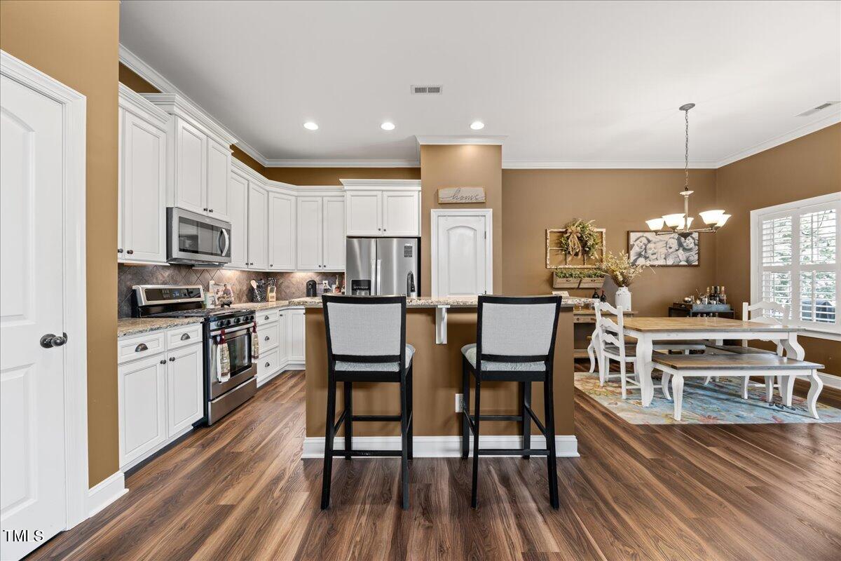 1300 Formal Garden Way Raleigh, NC 27603 - Photo 13 of 45 a kitchen with stainless steel appliances a stove a sink a refrigerator cabinets and wooden floor
