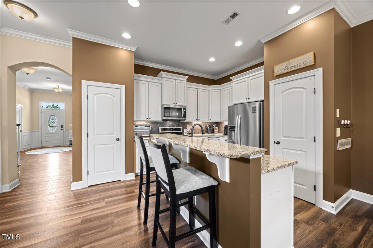 1300 Formal Garden Way Raleigh, NC 27603 - Photo 8 of 45 a kitchen with stainless steel appliances kitchen island granite countertop a refrigerator a stove top oven and a dining table with wooden floor