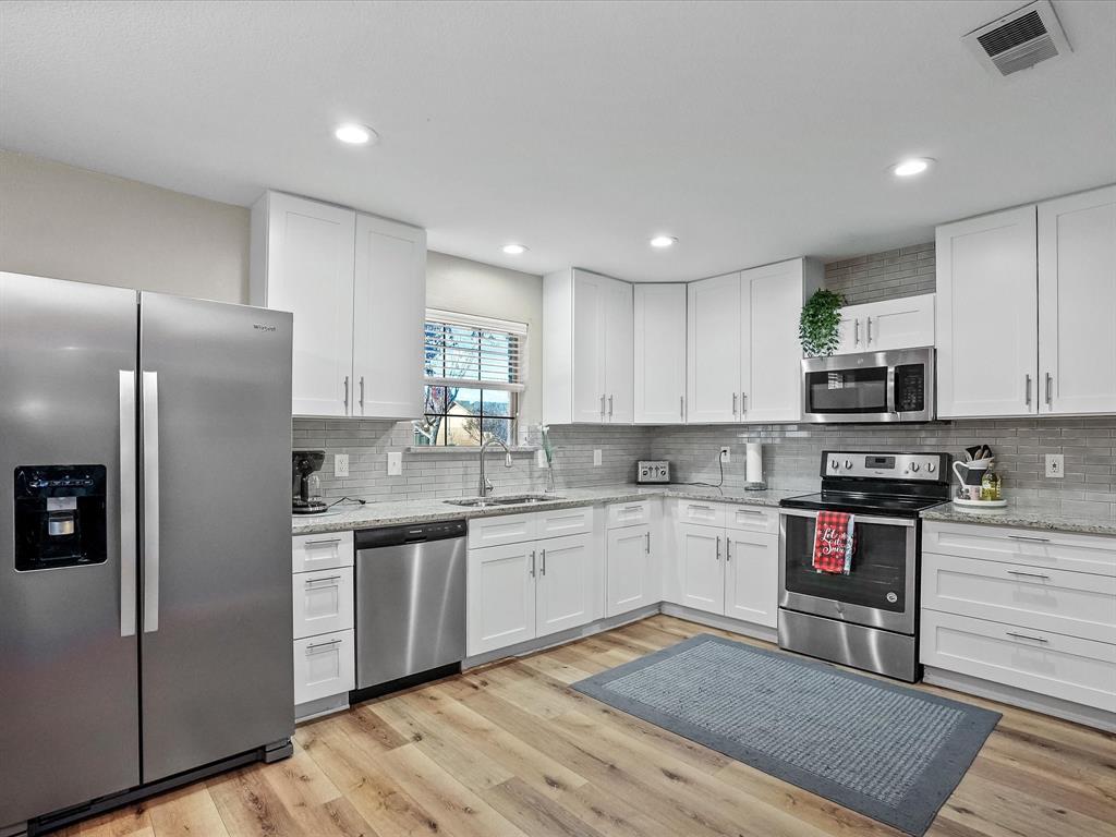 516 South Alabama Street Celina, TX 75009 - Photo 5 of 31 a kitchen with stainless steel appliances granite countertop a stove top oven a sink and dishwasher a refrigerator with wooden floor