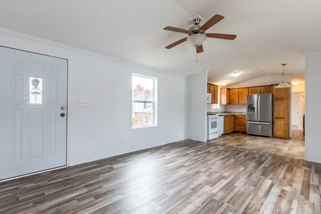 a view of a livingroom with a ceiling fan a kitchen a ceiling fan and wooden floor